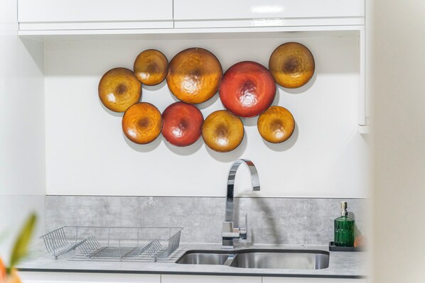 A kitchen with a stainless steel sink, a dish rack, and a wall-mounted decorative plate arrangement. - 2 Pump House (Birmingham)