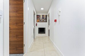 A hallway with a wooden door on the left, a fire extinguisher on the wall, and a television screen at the end. - 2 Pump House (Birmingham)