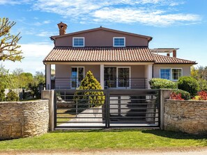 A two-story house with a tiled roof, a stone wall, and a metal gate. - Villa Nikolina by Interhome (Pula/Banjole)