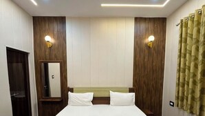 A bedroom with a bed, wooden panel walls, a ceiling fan, and wall-mounted lights. - Shri Ladli Stays Inn (Vrindavan)