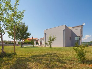 A modern building with a flat roof, surrounded by a grassy area with trees and a clear sky. - Villa Eva by Interhome (Pula/Banjole)