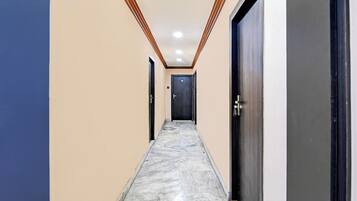 A hallway with a marble floor, beige walls, and wooden trim on the ceiling.