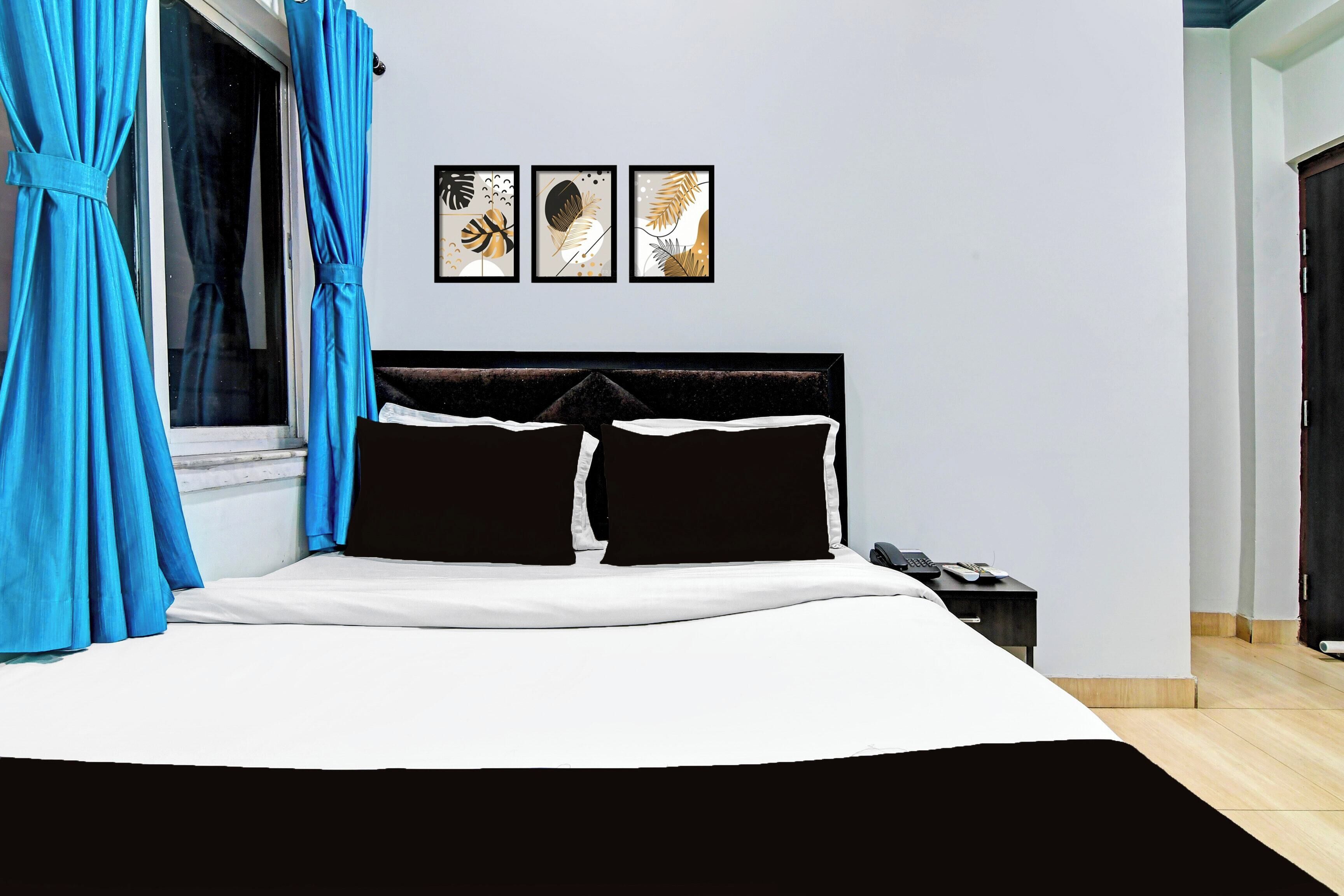 Une chambre à coucher comprenant un lit, une table de chevet et trois œuvres d’art accrochées au mur.