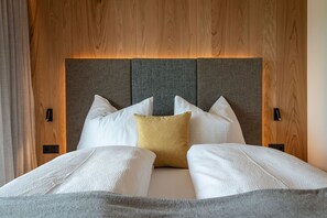 Una cama con cabecera, varias almohadas y una colcha.