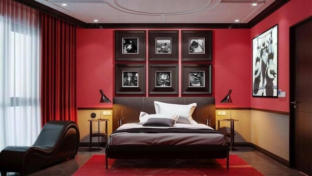 Un dormitorio moderno con una cama grande, un chaise lounge y una pared de acento roja.