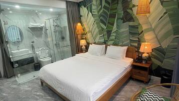 Un dormitorio moderno con una cama grande, una ducha con cerramiento de vidrio y una pared con diseño de hojas.
