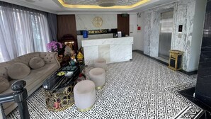 Un hall de hotel con una recepción, un sofá, un altar decorativo y un suelo estampado.