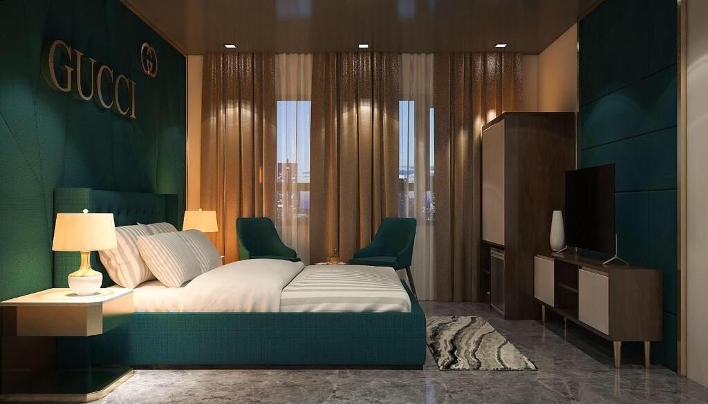 A hotel room with a bed, two chairs, a TV, and a wardrobe.