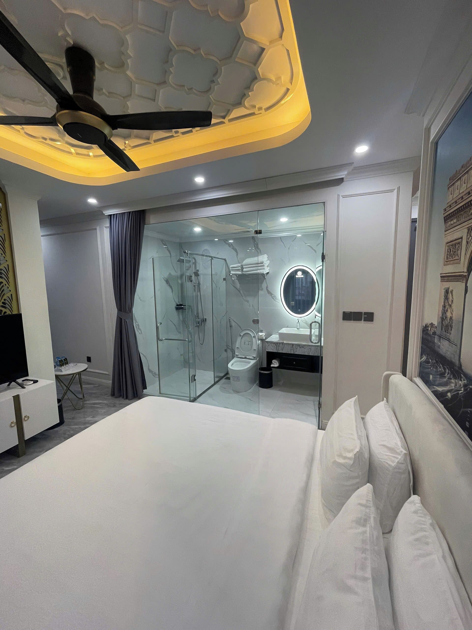 A modern bedroom with a large bed, a glass-enclosed shower, and a vanity with a mirror.