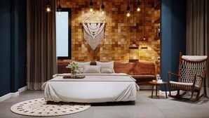 Un dormitorio con una cama grande, un cabecero de madera, una lámpara colgante y una silla.