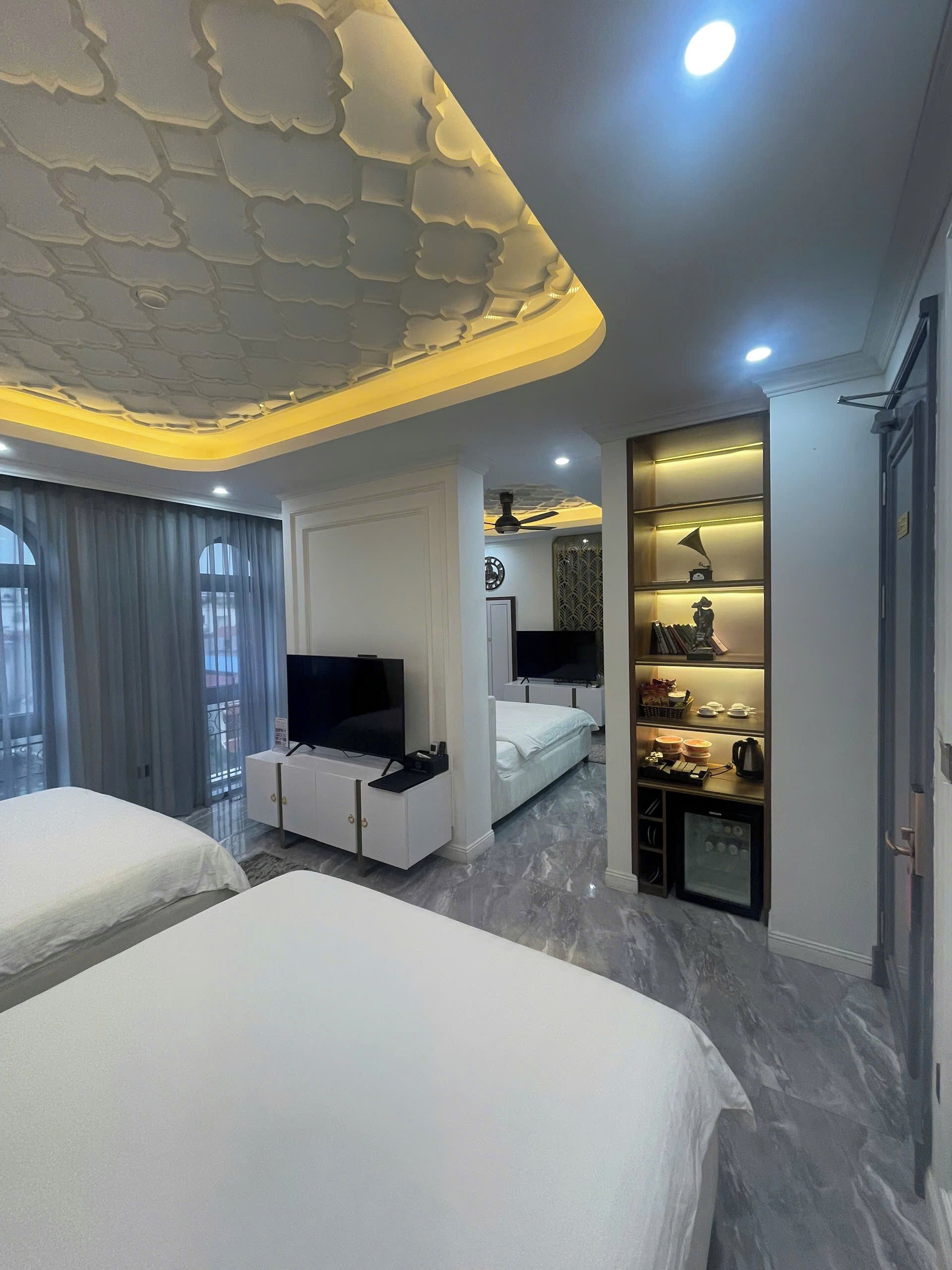 Une chambre d’hôtel avec deux lits, une télévision, un minibar et un plafond décoratif.