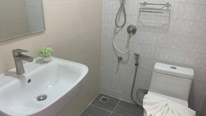 A bathroom with a white sink, a toilet, and a shower area.
