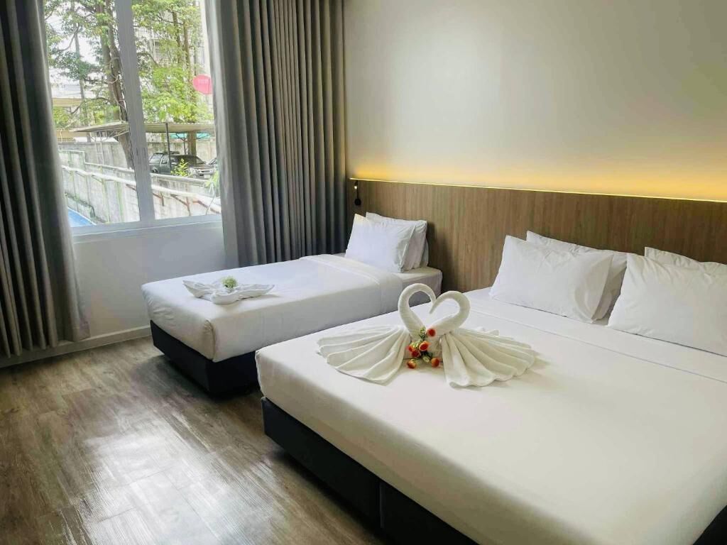 Habitación de hotel con dos camas, vista al exterior y una ventana con cortinas.