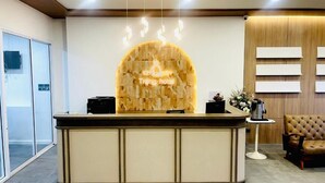 A reception desk with a wooden backdrop and a sign that reads 'Trang Hotel.'