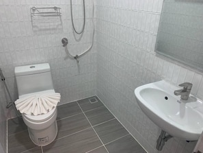 A bathroom with a toilet, shower, and sink.