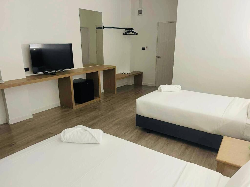 Une chambre d’hôtel avec un lit, une télévision, un banc et un miroir.