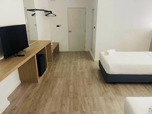 A hotel room with a bed, a TV, a desk, and a door.