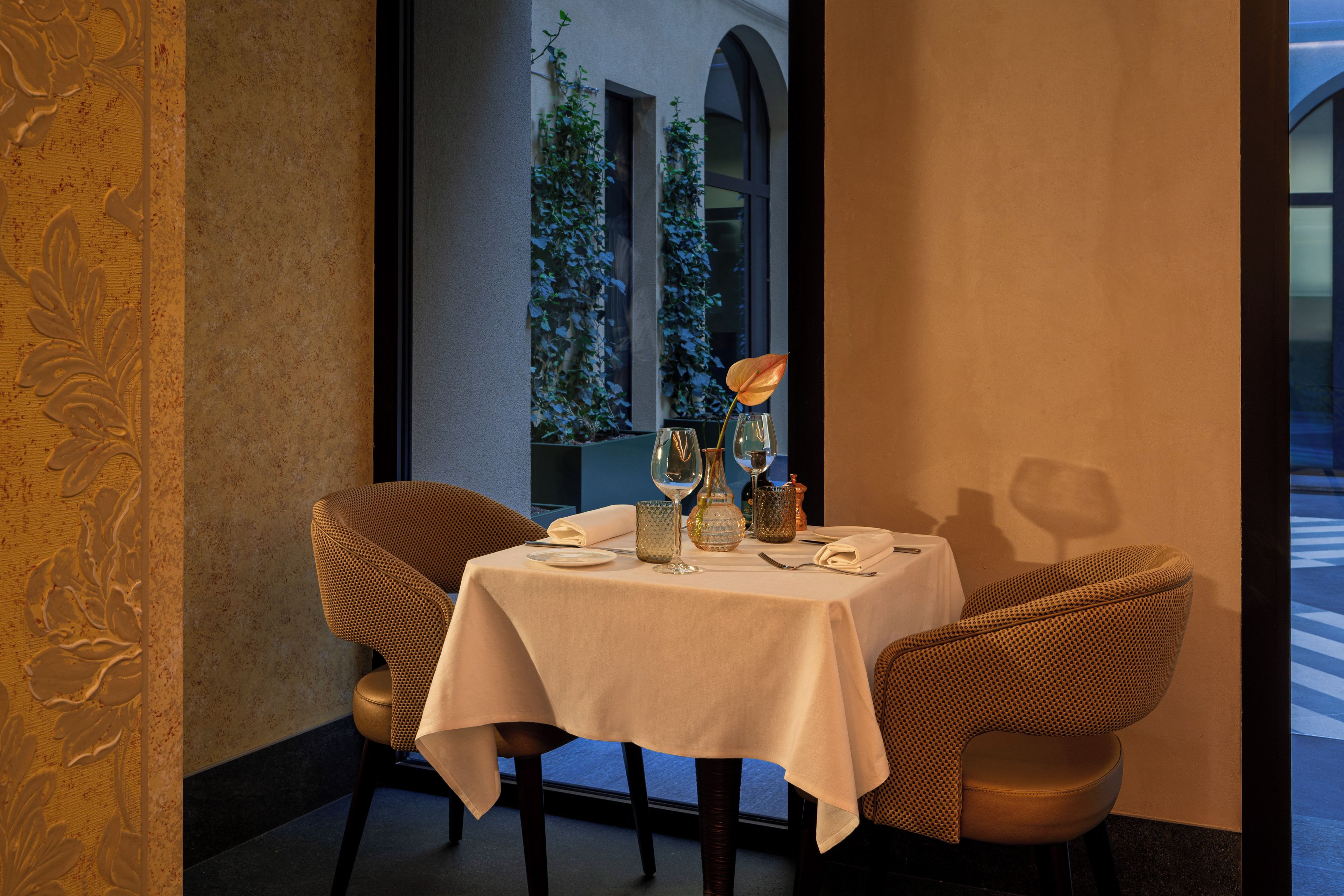 Une table à manger dressée avec une nappe blanche, deux chaises et divers éléments de vaisselle.