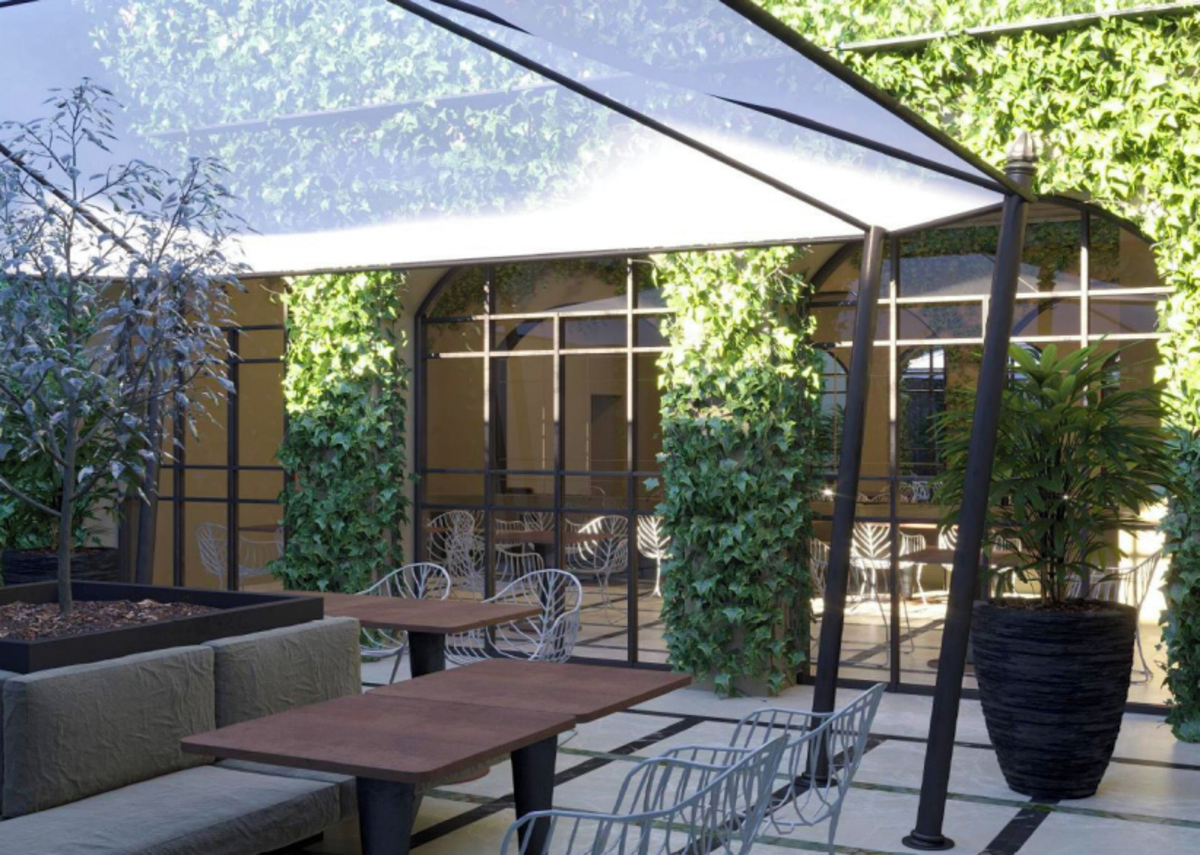 Un espace extérieur aménagé avec des tables et des chaises, entouré de verdure et protégé par une paroi de verre.