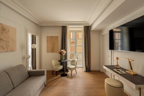 Uma sala de estar moderna com sofá, mesa redonda com cadeiras, televisão e uma grande janela com cortinas.
