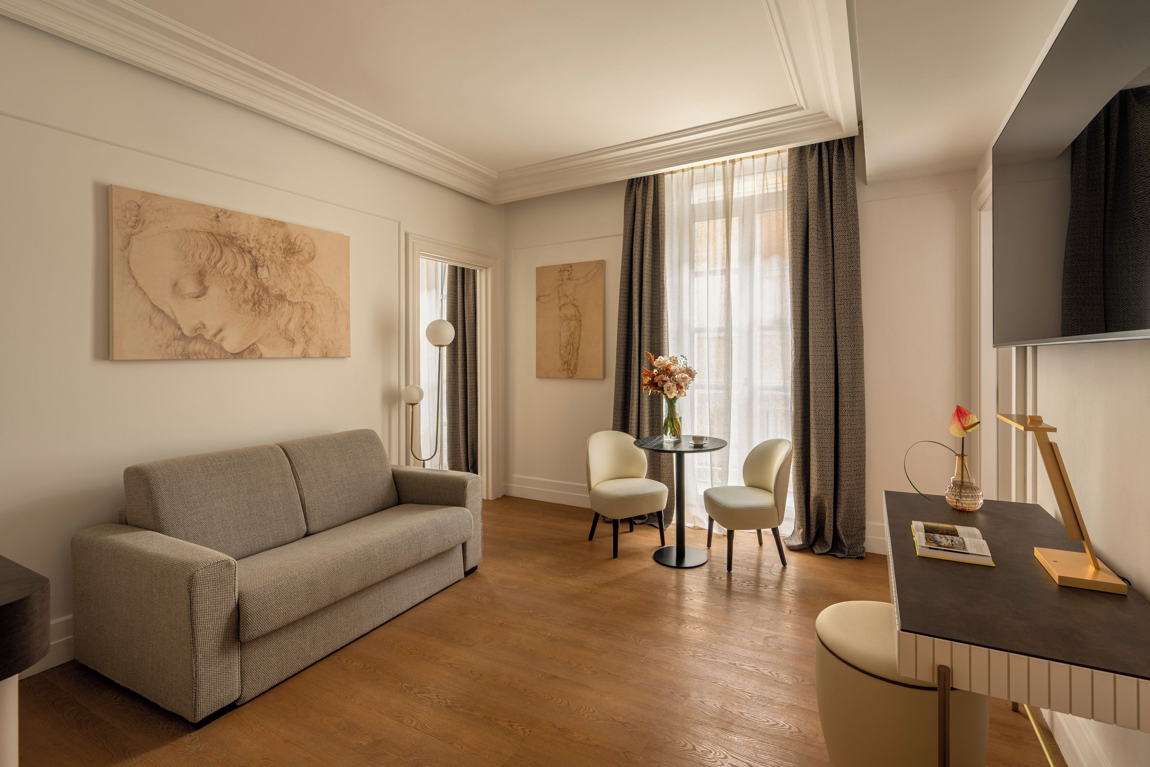 Ein modernes Wohnzimmer mit einer Couch, zwei Sesseln, einem kleinen Tisch und Kunstwerken an den Wänden.
