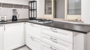 Una cocina moderna con armarios blancos, encimera negra y estufa integrada.