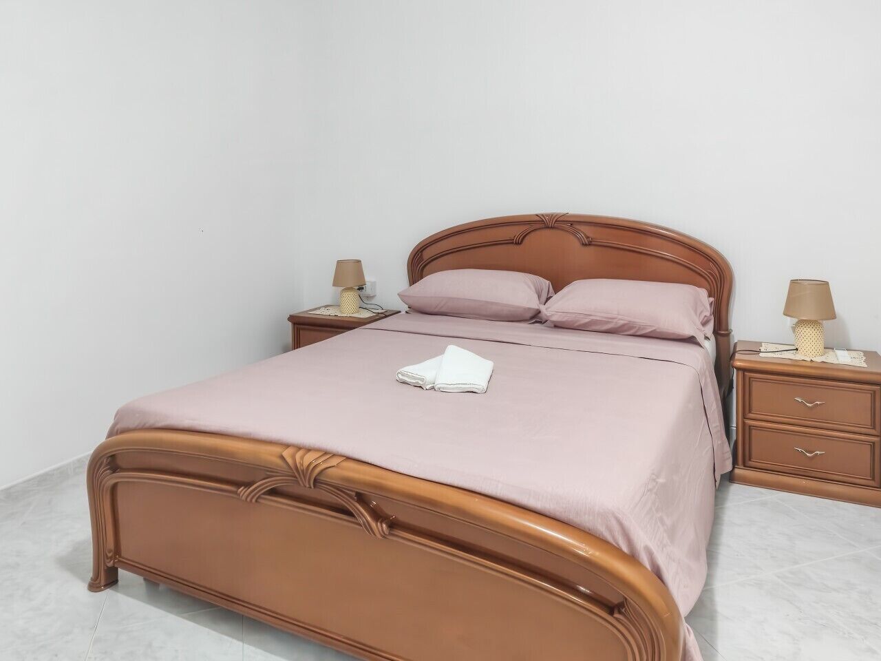 Una cama individual con cabecera, dos mesitas de noche y dos lámparas.
