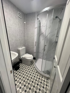 A bathroom with a curved glass shower enclosure, a toilet, and a sink. - Kent Hotel (Great Yarmouth)