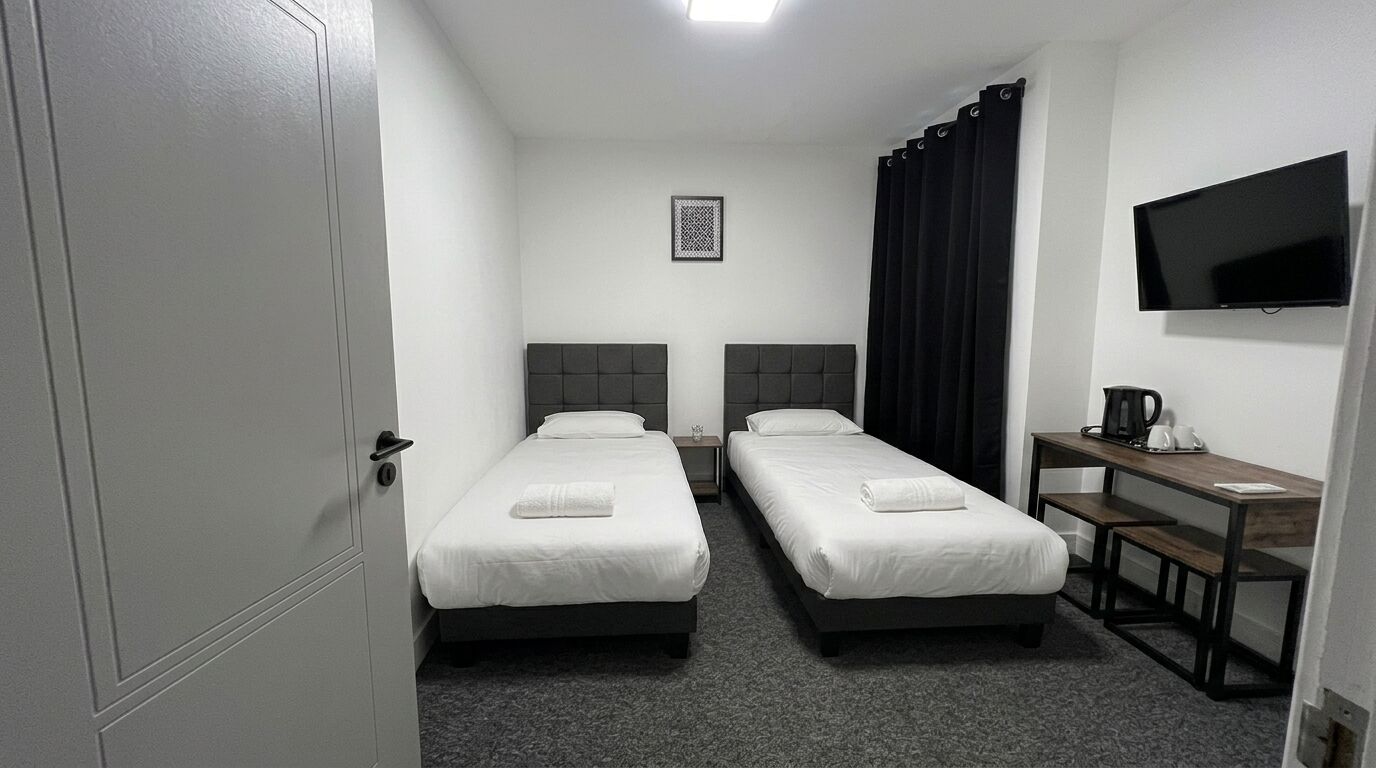 Une chambre d’hôtel avec deux lits simples, un bureau avec une chaise, une télévision à écran plat et une machine à café.