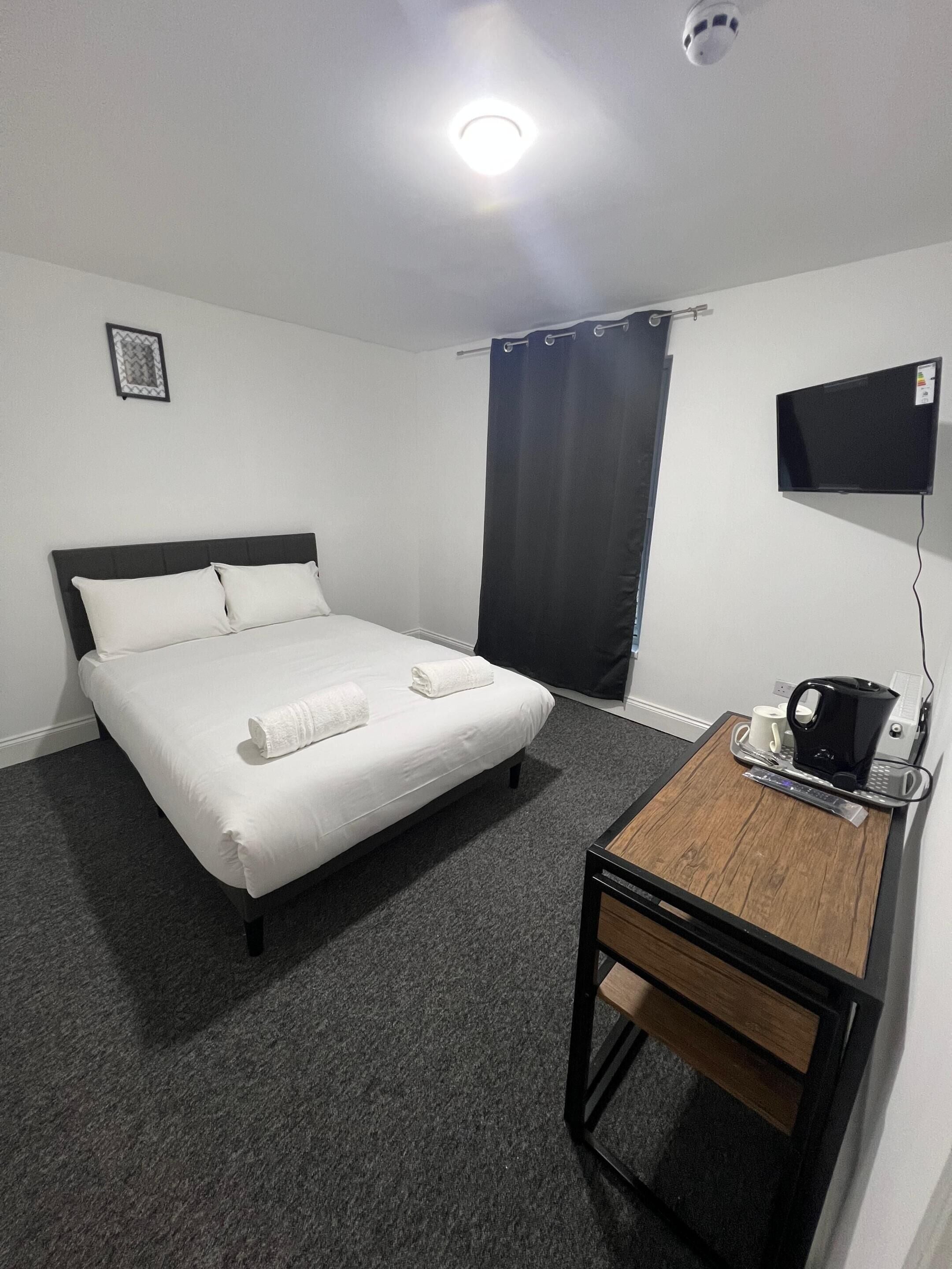 Une chambre d’hôtel équipée d’un lit, d’un bureau avec une machine à café et d’un téléviseur à écran plat.