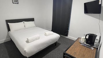 Une chambre d’hôtel équipée d’un lit, d’un bureau avec une machine à café et d’un téléviseur à écran plat.