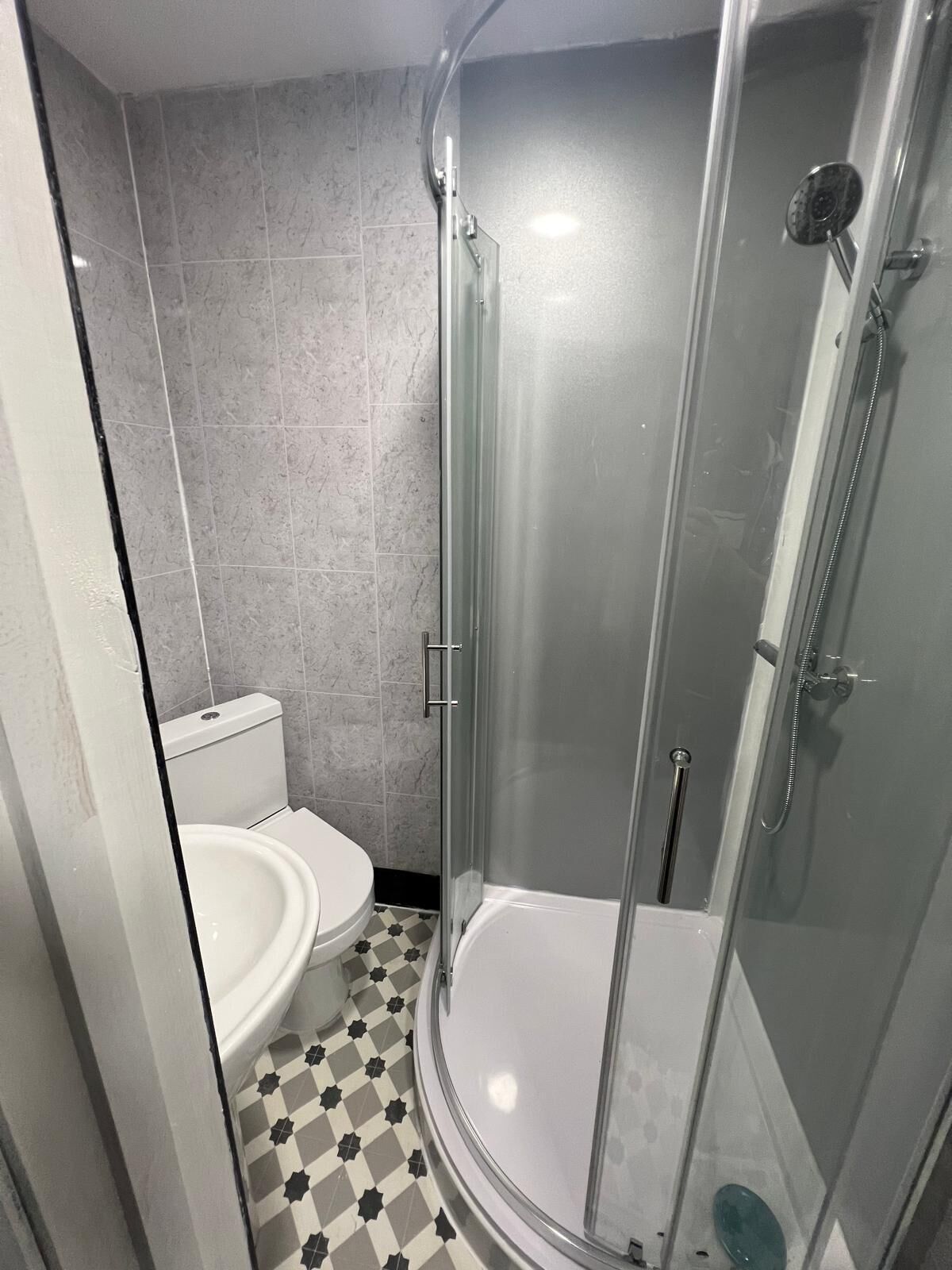 Une salle de bain avec une douche à parois de verre, des toilettes et un lavabo.