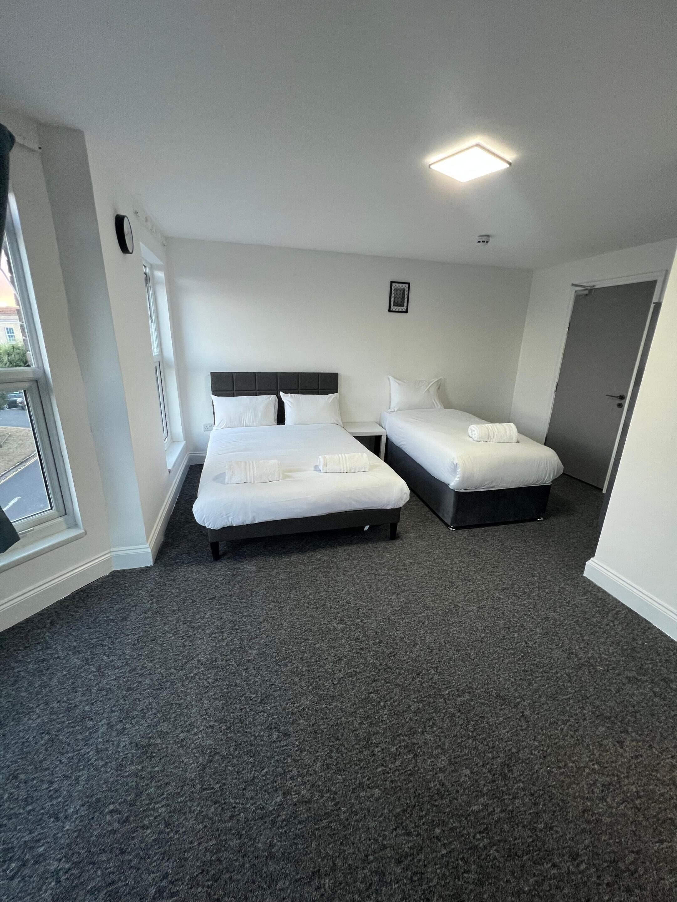 Une chambre d’hôtel avec deux lits, une fenêtre et une porte.