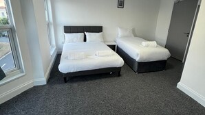 Habitación de hotel con dos camas, una ventana y una puerta.