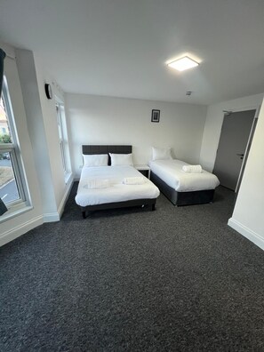Habitación de hotel con dos camas, una ventana y una puerta.