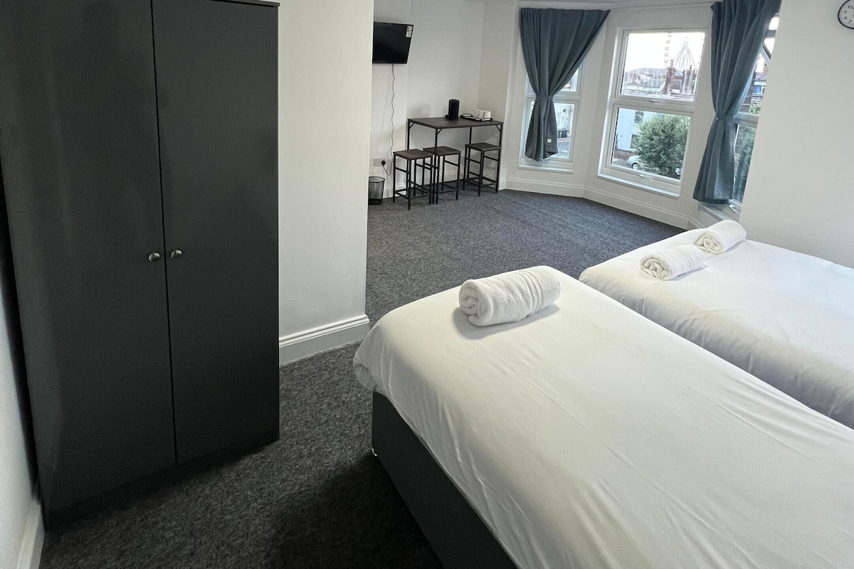 A hotel room with two beds, a desk, and a wardrobe.