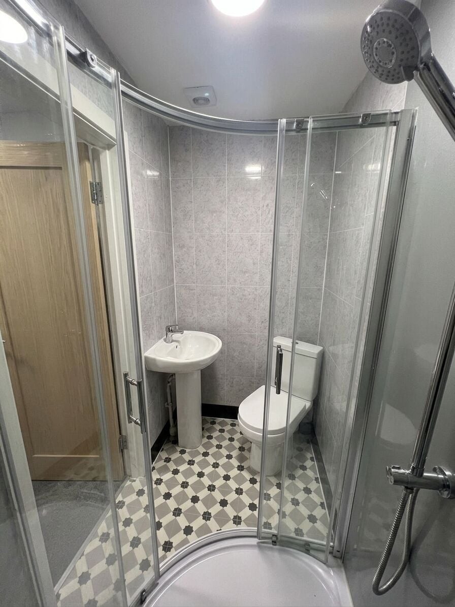 Une petite salle de bain avec une douche à parois de verre, un lavabo et des toilettes.
