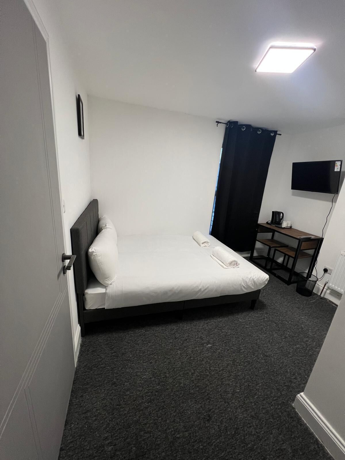 Une petite chambre avec un lit simple, un bureau et un téléviseur.