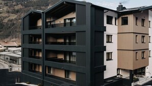 En bygning med flere etager, altaner, store vinduer og udsigt til et bjergrigt landskab.