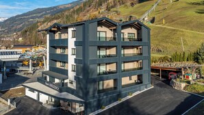 Et hotel med flere etager, altaner, parkeringsplads og en stolelift i baggrunden.