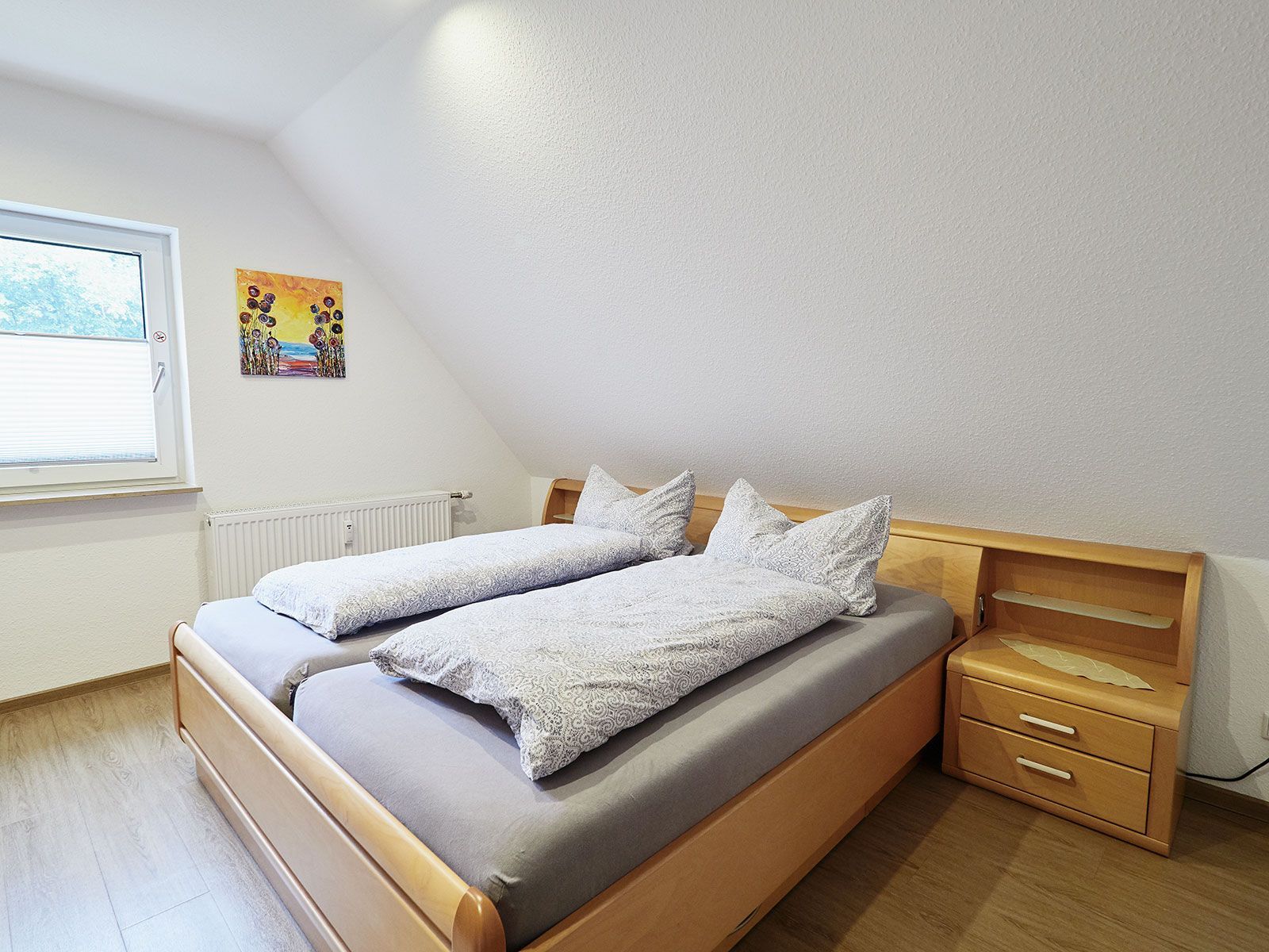 Ein Schlafzimmer mit einem Bett, einem Nachttisch und einem Fenster.