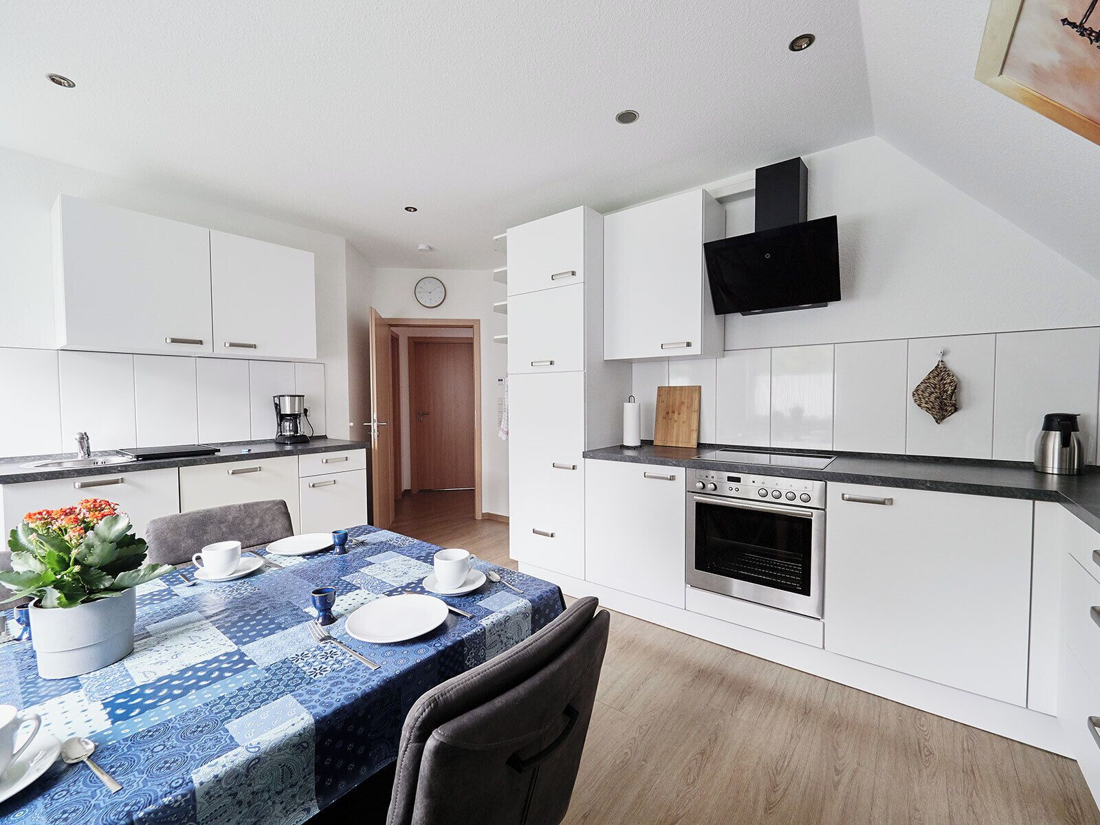A modern kitchen with white cabinets, a built-in oven, and a flat-screen TV mounted above the stove.