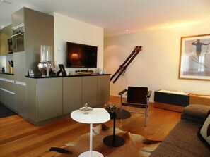 A modern living room with a sofa, a coffee table, and a TV mounted on the wall. - Ladina 34 Appartement/Fewo, Dusche oder Bad, WC 2½-Zimmerwohnung by Interhome (Davos)