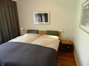 A hotel room with a bed, two bedside tables, a wall-mounted picture, and a curtain. - Ladina 34 Appartement/Fewo, Dusche oder Bad, WC 2½-Zimmerwohnung by Interhome (Davos)