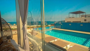 A pool area with lounge chairs and a view of the sea.
