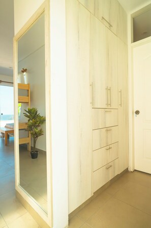 Une pièce avec une armoire blanche, une porte et une plante en pot.