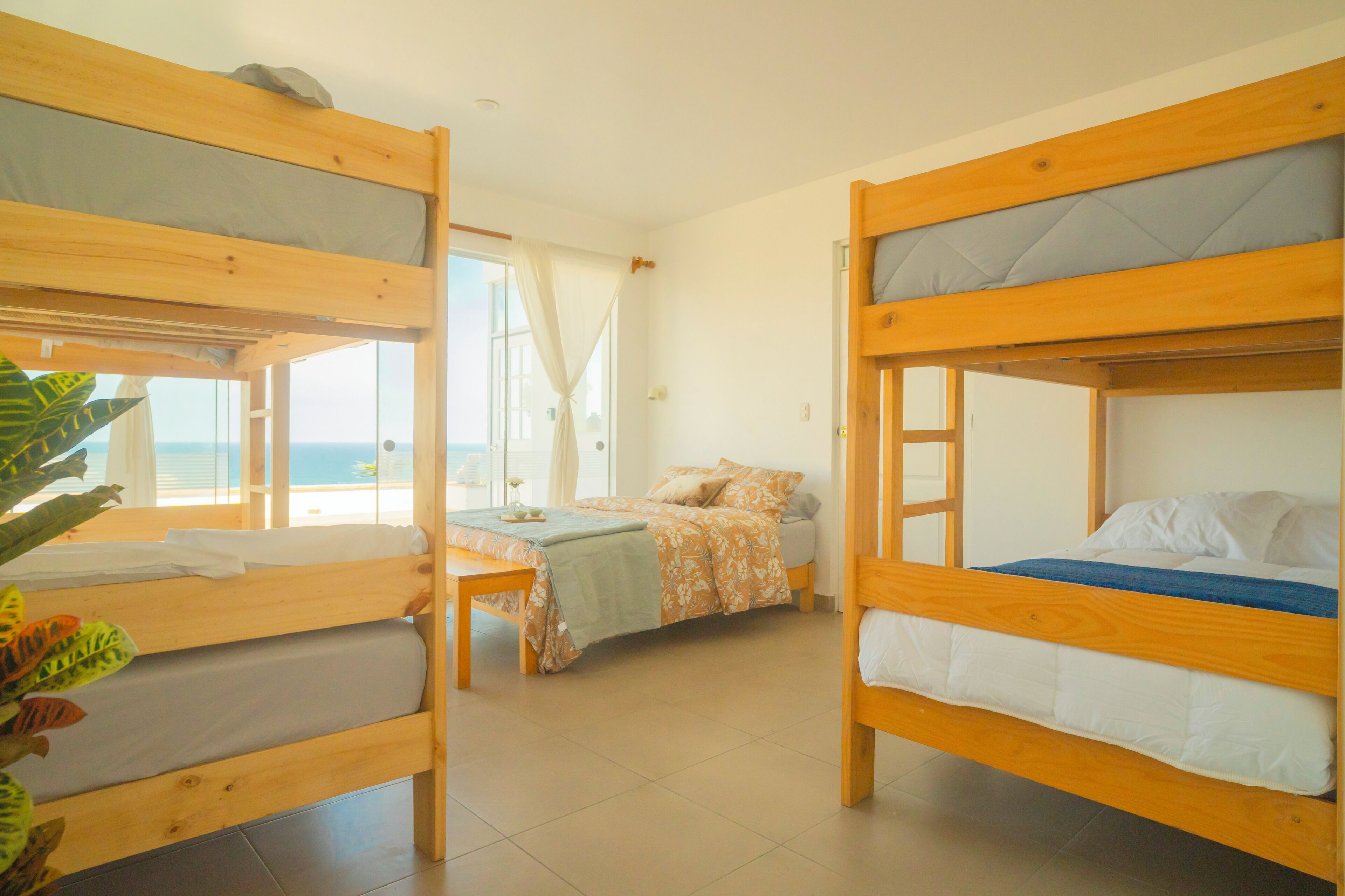 Una habitación con dos literas, una mesita y una ventana con cortinas.