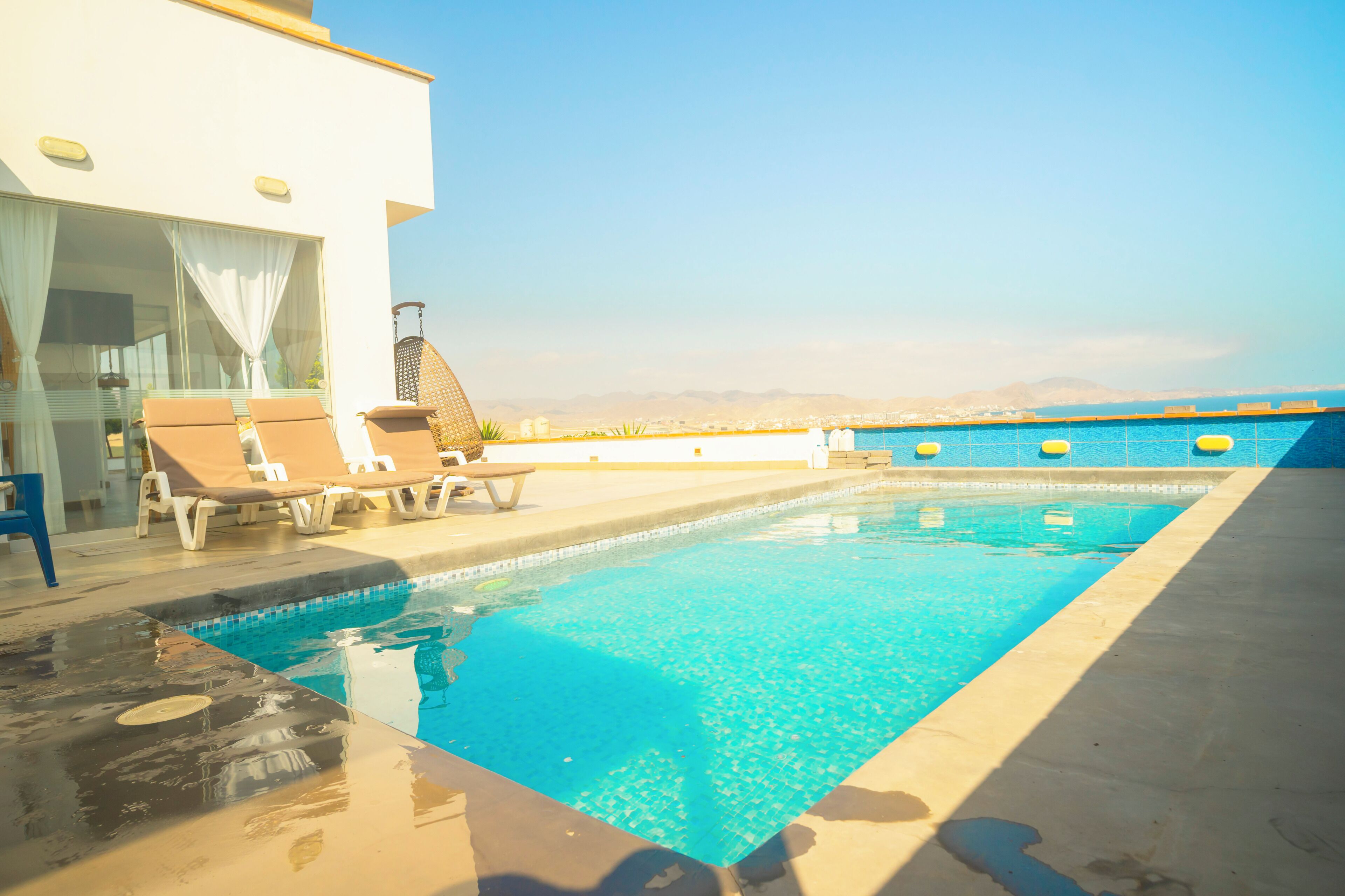 A swimming pool with lounge chairs and a view of the cityscape.