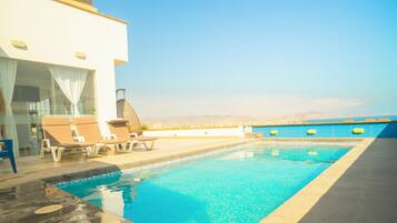 A swimming pool with lounge chairs and a view of the cityscape.