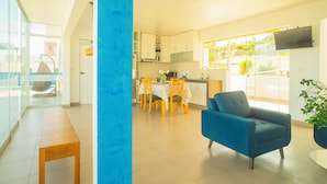 A modern living room with a blue chair, a wooden table, and a kitchen area in the background.